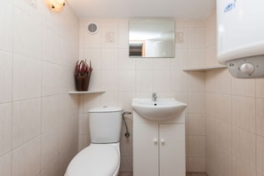 Un baño pequeño con inodoro, lavamanos y un dispensador de papel higiénico en la pared.