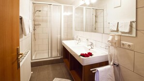 A modern bathroom with a walk-in shower, a large sink with a mirror, and a towel rack. - Apartment in Ischgl With Parking Space (Ischgl)