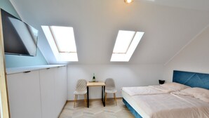 A bedroom with a bed, a desk, two chairs, a TV, and skylights. - Comfortable Holiday Studio Close to the Beach (Ustronie Morskie)