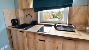 A modern kitchen with a wooden countertop, black sink, and a window with a view of buildings. - Comfortable Holiday Studio Close to the Beach (Ustronie Morskie)