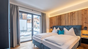 A hotel room with a large bed, wooden panel walls, and a view of a snowy outdoor area. - Chalet in Wald Near Krimml Waterfalls (Wald im Pinzgau)