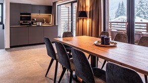 A modern kitchen with dark cabinets and a wooden dining table with chairs. - Chalet in Wald Near Krimml Waterfalls (Wald im Pinzgau)