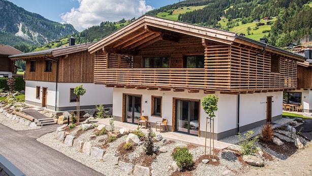 A wooden chalet with a sloped roof, large windows, and a stone pathway leading to the entrance. - Chalet in Wald Near Krimml Waterfalls (Wald im Pinzgau)