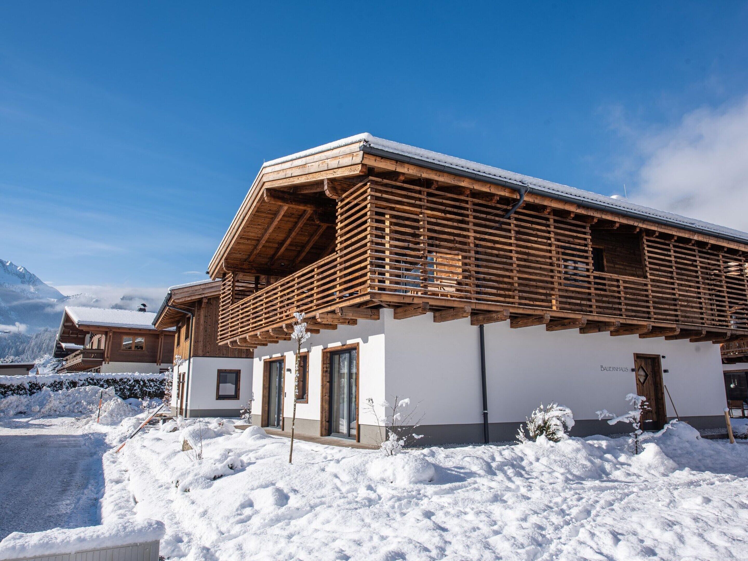 Un bâtiment de style chalet, doté d’un balcon en bois, de murs blancs et d’un toit recouvert de neige.