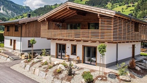 A modern wooden chalet with a balcony, large windows, and a view of the surrounding mountains. - Chalet in Wald Near Krimml Waterfalls (Wald im Pinzgau)