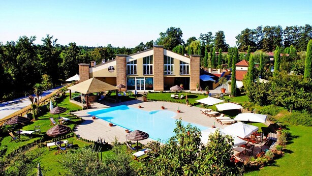 Un grande edificio con piscina, circondato da rigogliosa vegetazione e zone relax all'aperto.