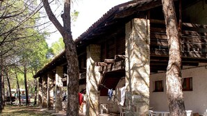 A rustic building with stone pillars and wooden beams, outdoor seating, and a clothesline. - Grado Apartment in Belvedere Resort (Aquileia)