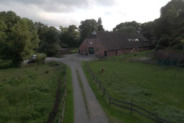 A rural barn with a dirt road leading to it, surrounded by green fields and trees.