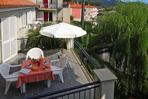 A balcony with a table set for breakfast, including croissants, fruit, and coffee. - Apartment in San Bartolomeo Al Mare (San Bartolomeo al Mare)