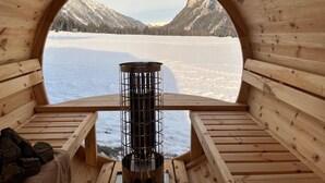 Un igloo en bois doté d’une fenêtre circulaire, d’un chauffage métallique et d’un banc.