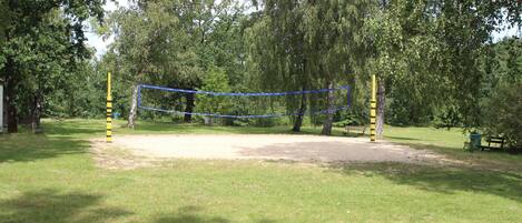 Una red de voleibol en un parque con árboles y un banco.