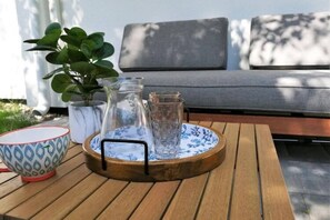 Et træbord med en bakke, der indeholder en kande, et glas og en skål med mønster.