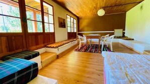Une pièce chaleureuse avec un plancher en bois, un banc, une table avec des chaises et de grandes fenêtres.