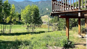 Une structure de pergola en bois offrant une vue sur un champ verdoyant et des arbres en arrière-plan.