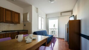 A compact kitchen with wooden cabinets, a dining table with purple chairs, and a built-in oven. - Apartments Condominio Diana, Bibione Lido del Sole-formerly TUI Ferienhaus (San Michele al Tagliamento)