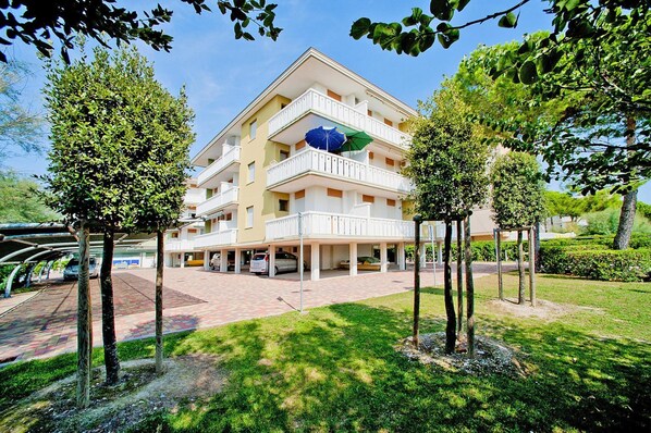 Ett hotell med flera våningar, en central innergård, ett tak över parkeringsområdet och ett stort parasoll på balkongen.