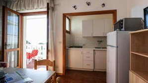 A compact kitchen with white cabinets, a refrigerator, and a stove. - Apartments Condominio Diana, Bibione Lido del Sole-formerly TUI Ferienhaus (San Michele al Tagliamento)