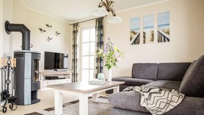 Un salon moderne avec une cheminée, un canapé, un téléviseur et des œuvres d’art décoratives au mur.