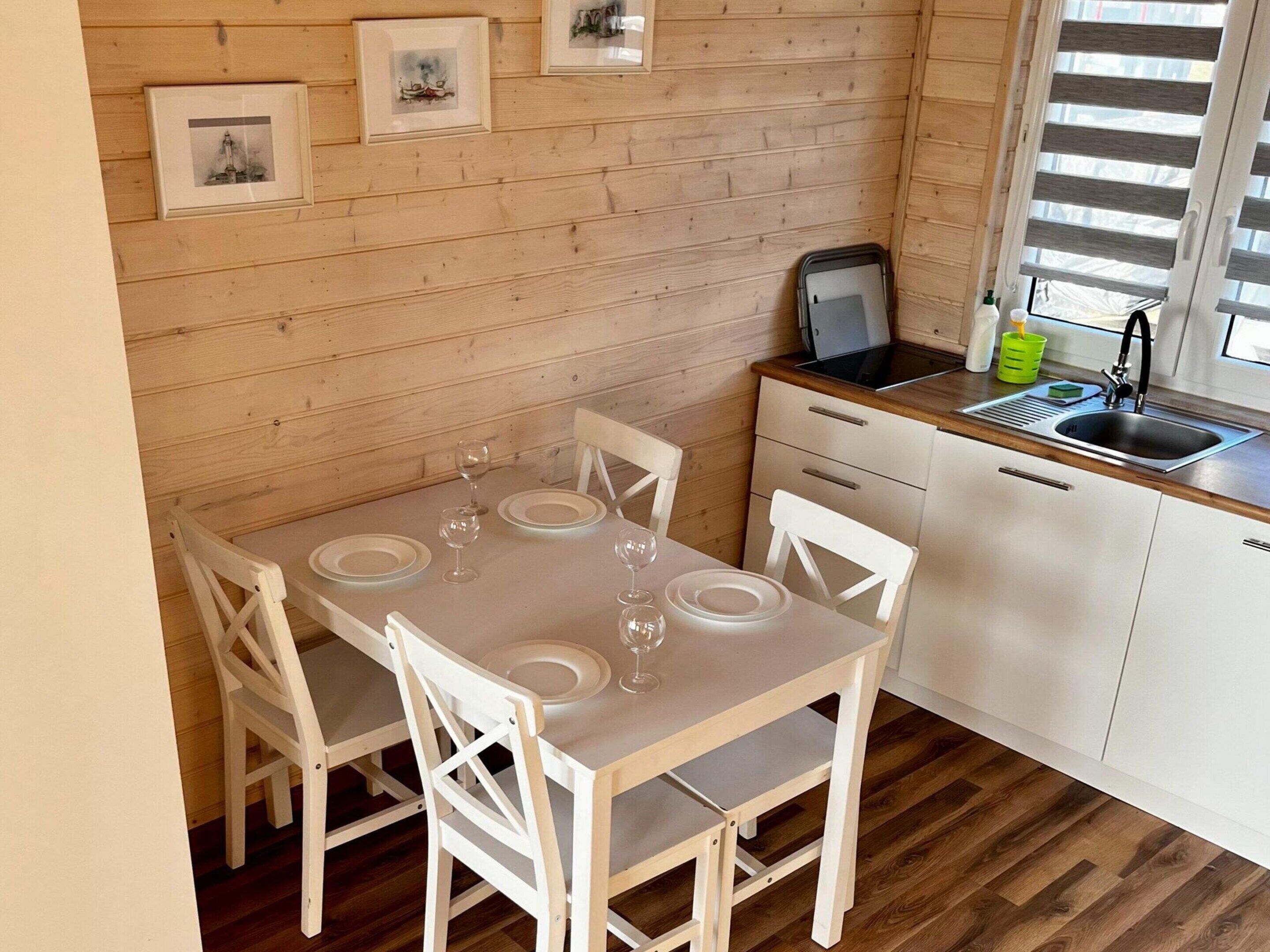 Eine kleine Küche mit Essbereich, Holzwänden und einem Fenster mit Jalousien.