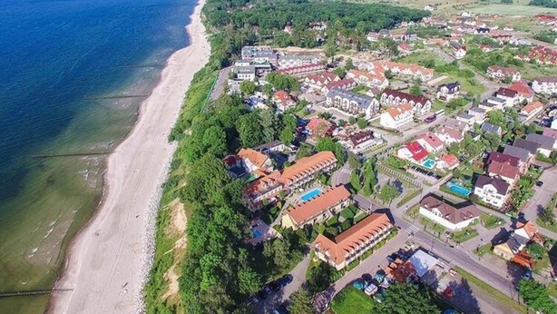Vue aérienne d’une zone résidentielle côtière, avec des maisons, une plage et une route.