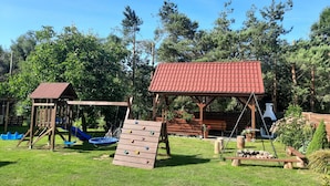 Un’area giochi con altalene, una parete da arrampicata e un piccolo padiglione con tetto rosso.