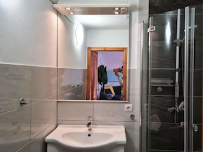 A modern bathroom with a large mirror, a sink, and a glass shower enclosure. - Ferienhaus, Zinnowitz (Zinnowitz)