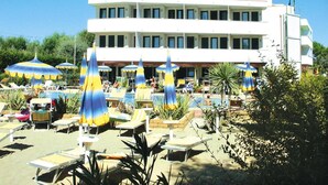 Et hotel med poolområde, flere liggestole og parasoller.