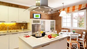 Une cuisine moderne dotée d’un îlot central, de meubles blancs et d’un coin repas avec une table et des chaises.
