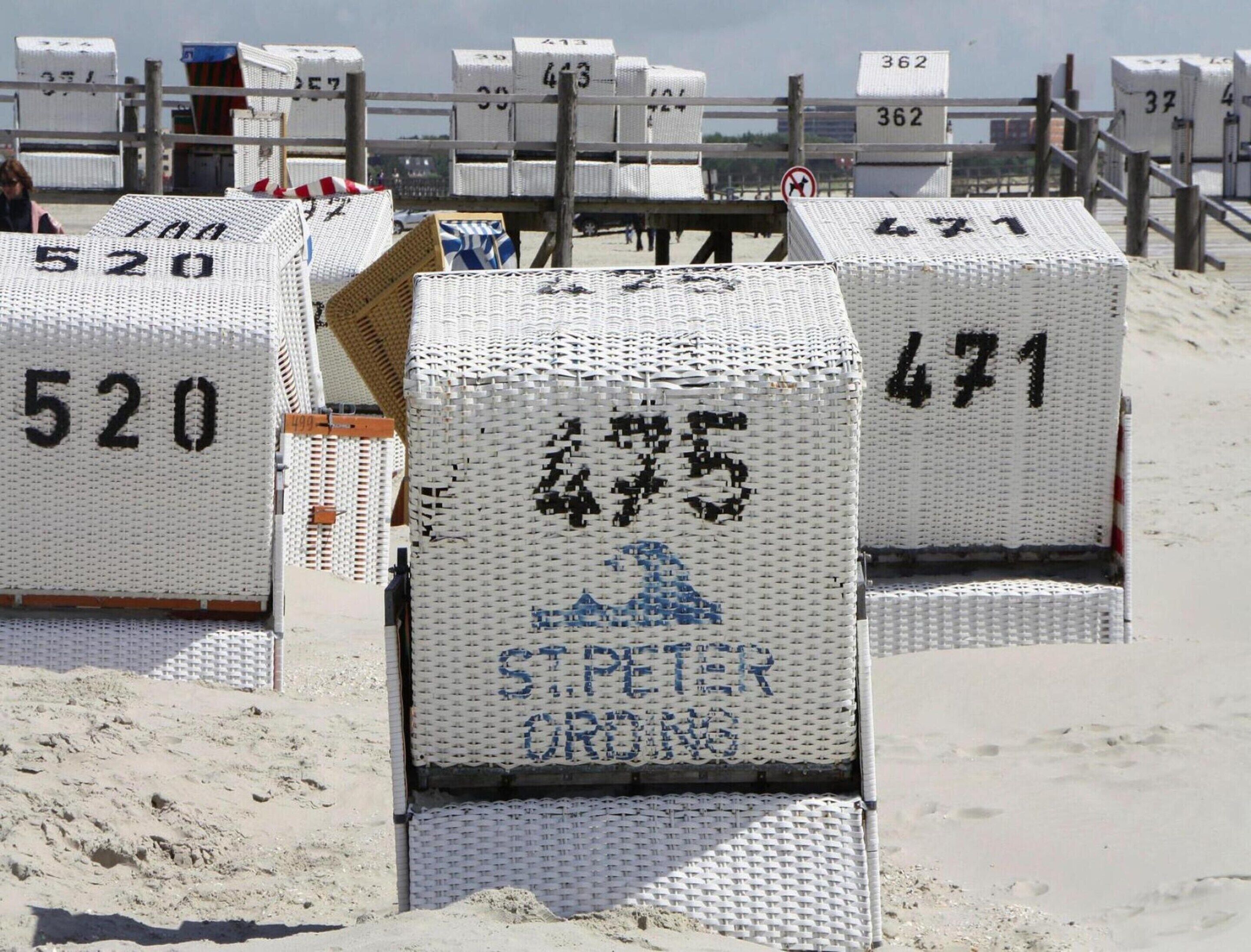 Cadeiras de praia numeradas à beira-mar, com uma placa que diz "ST.PETER ORDINANCE".
