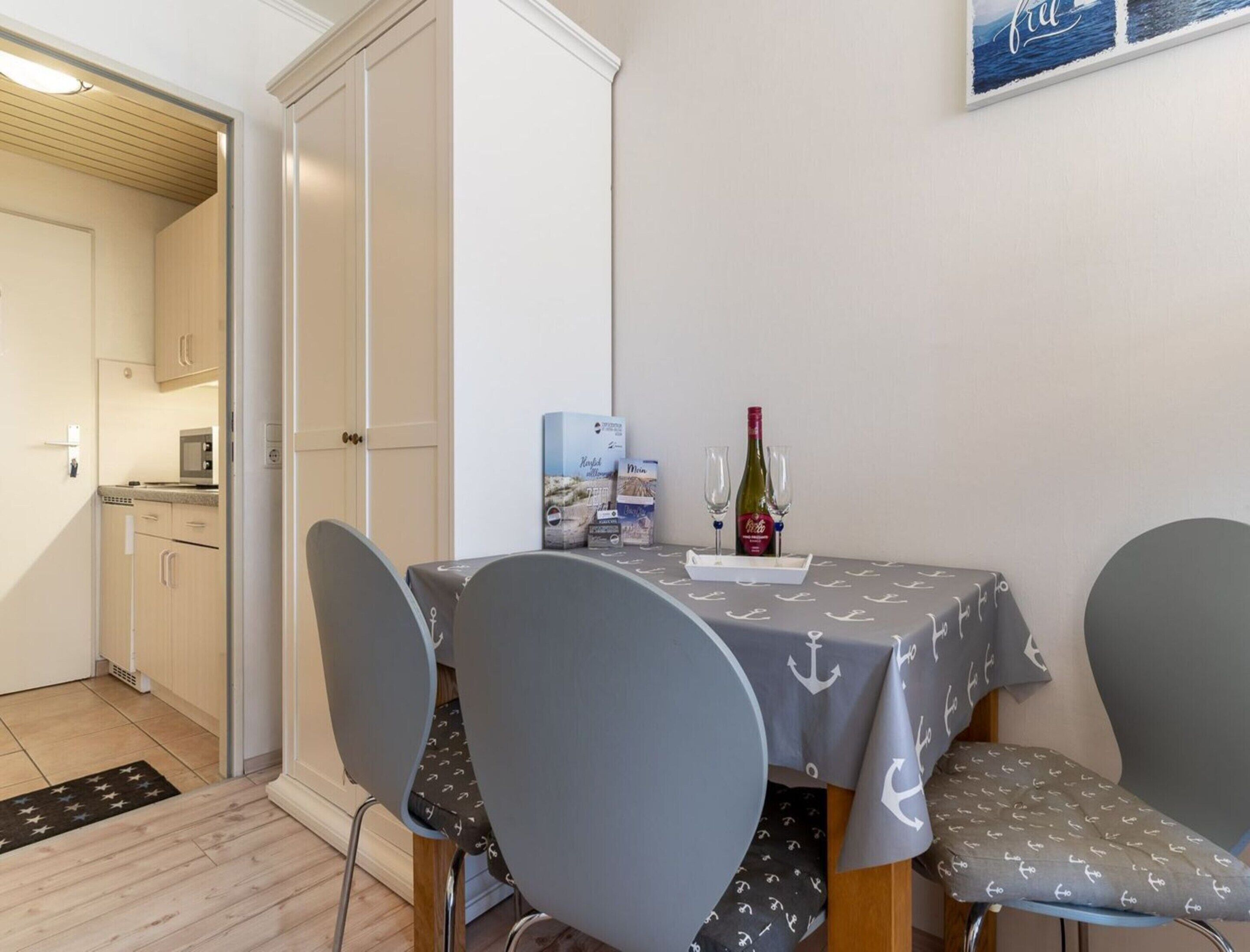 A dining area with a table set for two, a bottle of wine, and a box of chocolates.