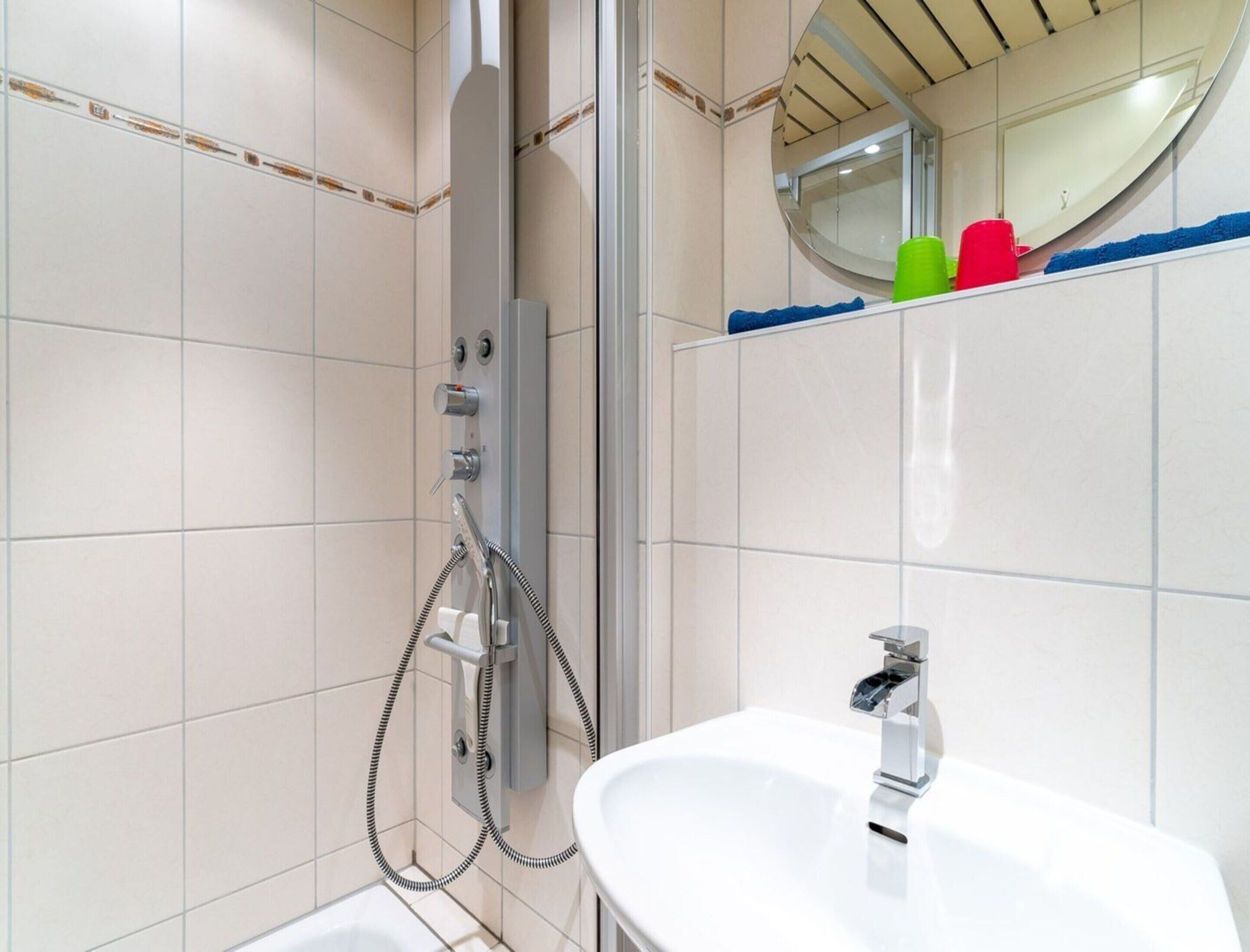 A bathroom with a shower, a sink, and a mirror.