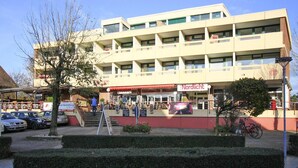 A multi-story building with a flat roof and a red awning. - Ferienwohnung, St. Peter - Ording (St. Peter-Ording)