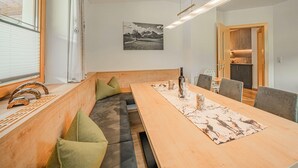 Ett modernt matområde med ett långt träbord, bekväma sittplatser och utsikt över köket.
