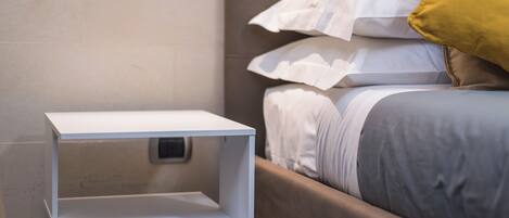 A neatly made bed with white and gray bedding, a brown headboard, and a yellow pillow.