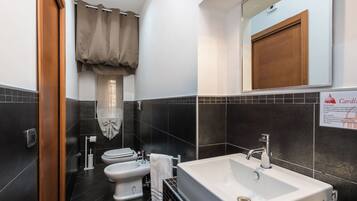A modern bathroom with a white sink, a bidet, and a toilet.