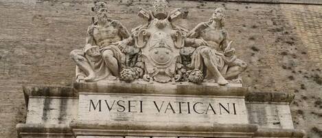 Fachada de piedra con la inscripción “MVSEI VATICANI” y un relieve escultórico en la parte superior.