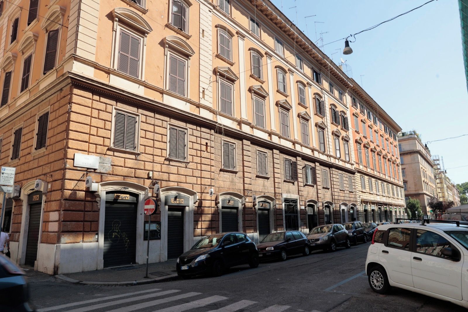 Ein mehrgeschossiges Gebäude mit einer Reihe geschlossener Geschäfte und einer Straße davor.