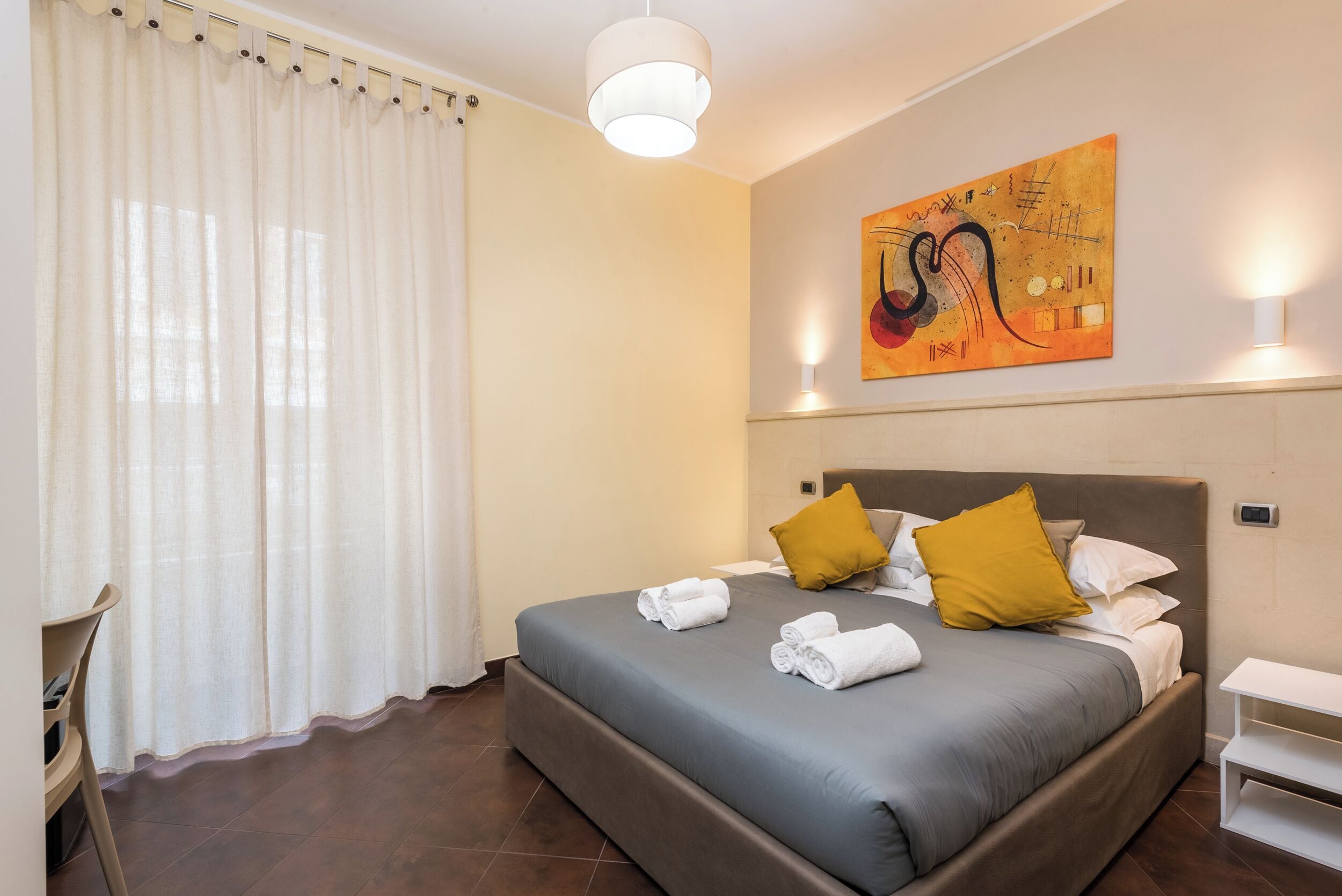 Una camera da letto con un letto, cuscini, un quadro e un comodino.