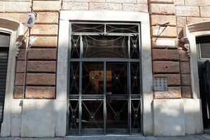 A building facade with a large arched window featuring intricate metalwork. - Cardinal Vatican INN (Rome)