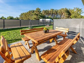 An outdoor patio with a wooden table and benches, surrounded by a fence and trees. - Comfortable Holiday Complex in Jastrzebia Gora (Wladyslawowo)