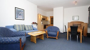 Una sala de estar con sofá, sillón y una pequeña mesa de comedor.