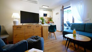 Un salon moderne avec un téléviseur, un canapé et un coin repas.