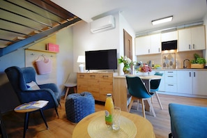 A modern living space with a sofa, a dining table, a TV, and a kitchen area. - Comfortable Holiday Homes With Terraces, Mielenko (Mielno)