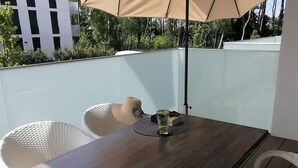 A dining area with a table and chairs, an umbrella, and a glass of water. - Holiday Houses for 4 People in Rewal-formerly TUI Ferienhaus (Rewal)