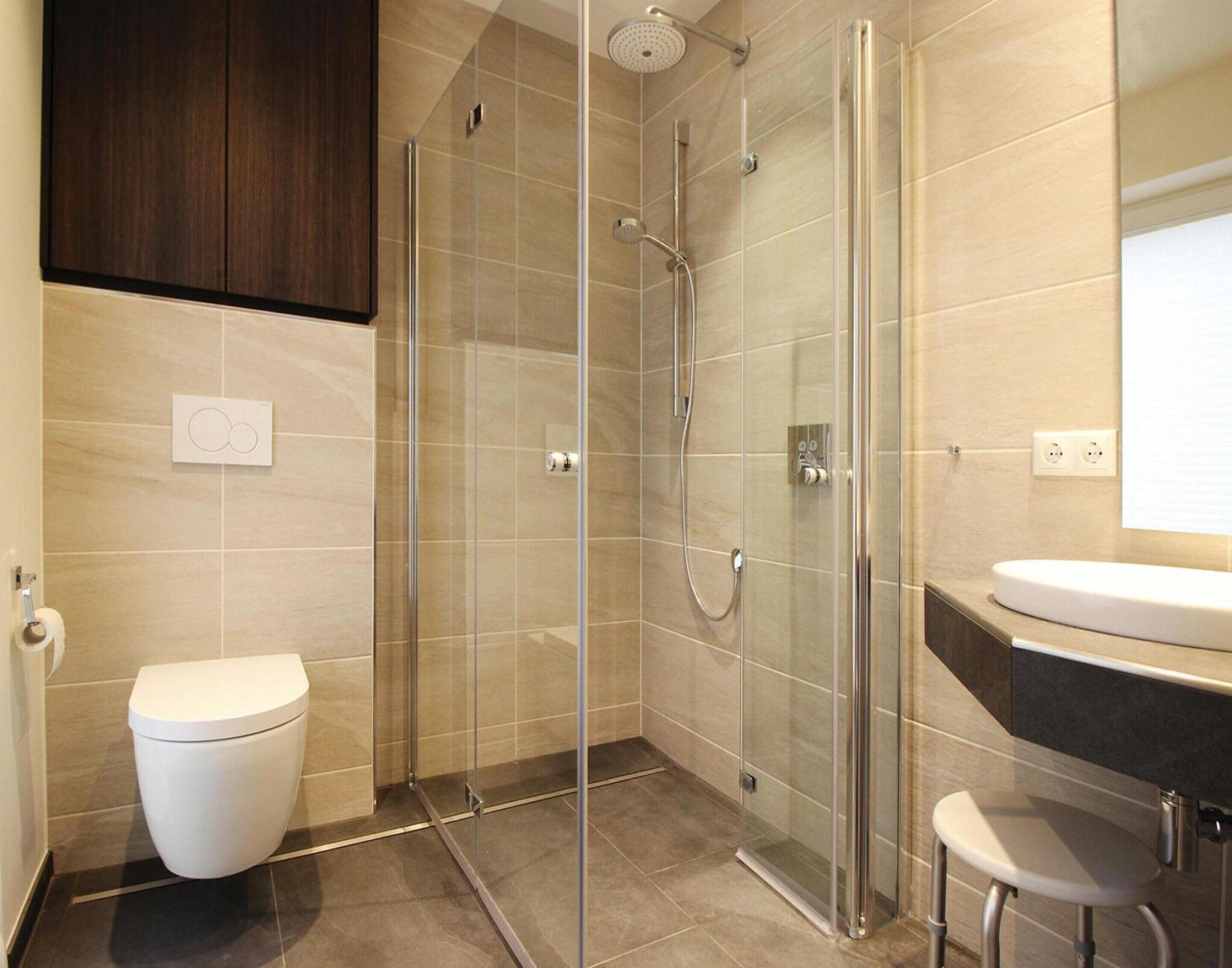 Une salle de bain moderne avec une douche à parois de verre, des toilettes et un lavabo.