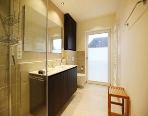 Une salle de bain moderne avec une douche à parois de verre, un meuble-lavabo et des toilettes.