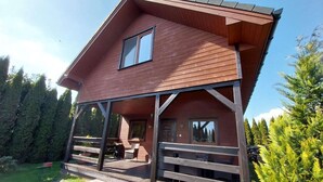 Ein zweistöckiges Holzhaus mit Balkon, umgeben von viel Grün.