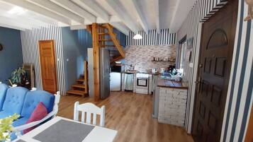 A compact living space with a kitchen, dining area, and a staircase leading to an upper level.