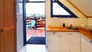 A kitchen with white cabinets, a wooden countertop, a sink, and a window above the sink. - Apartment in Jezierzany Near Lake Wicko (Postomino)