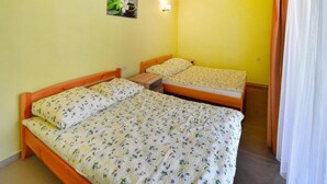 A room with two single beds, a small table, a wall-mounted light, and a picture of flowers. - Spacious Holiday Home With Private Garden (Mielno)